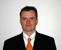 A man in a suit and tie standing up against a wall.